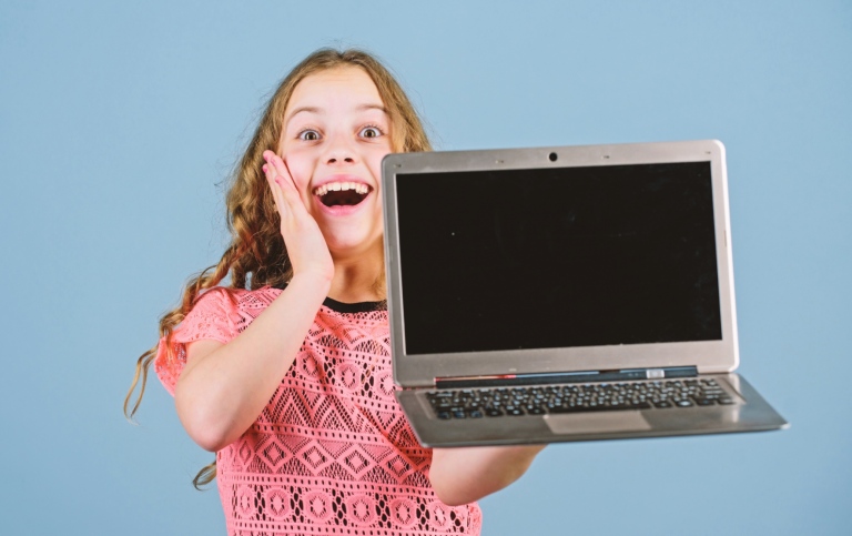 Glad flicka som visar upp en öppen laptop.