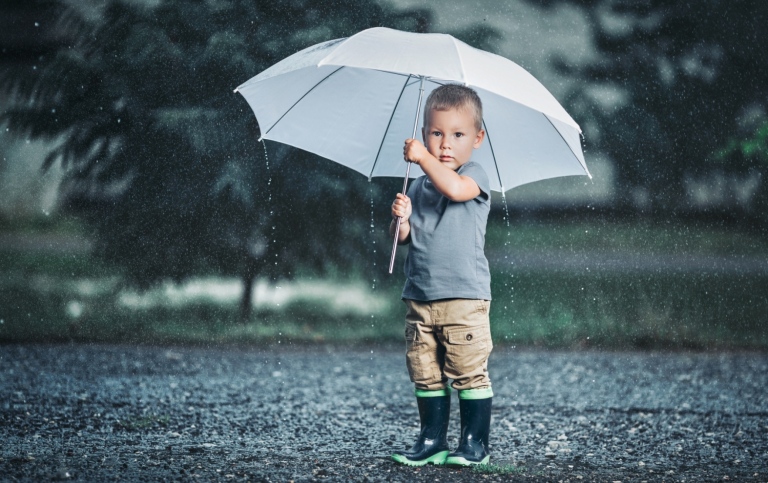 Pojke som står utomhus med ett paraply